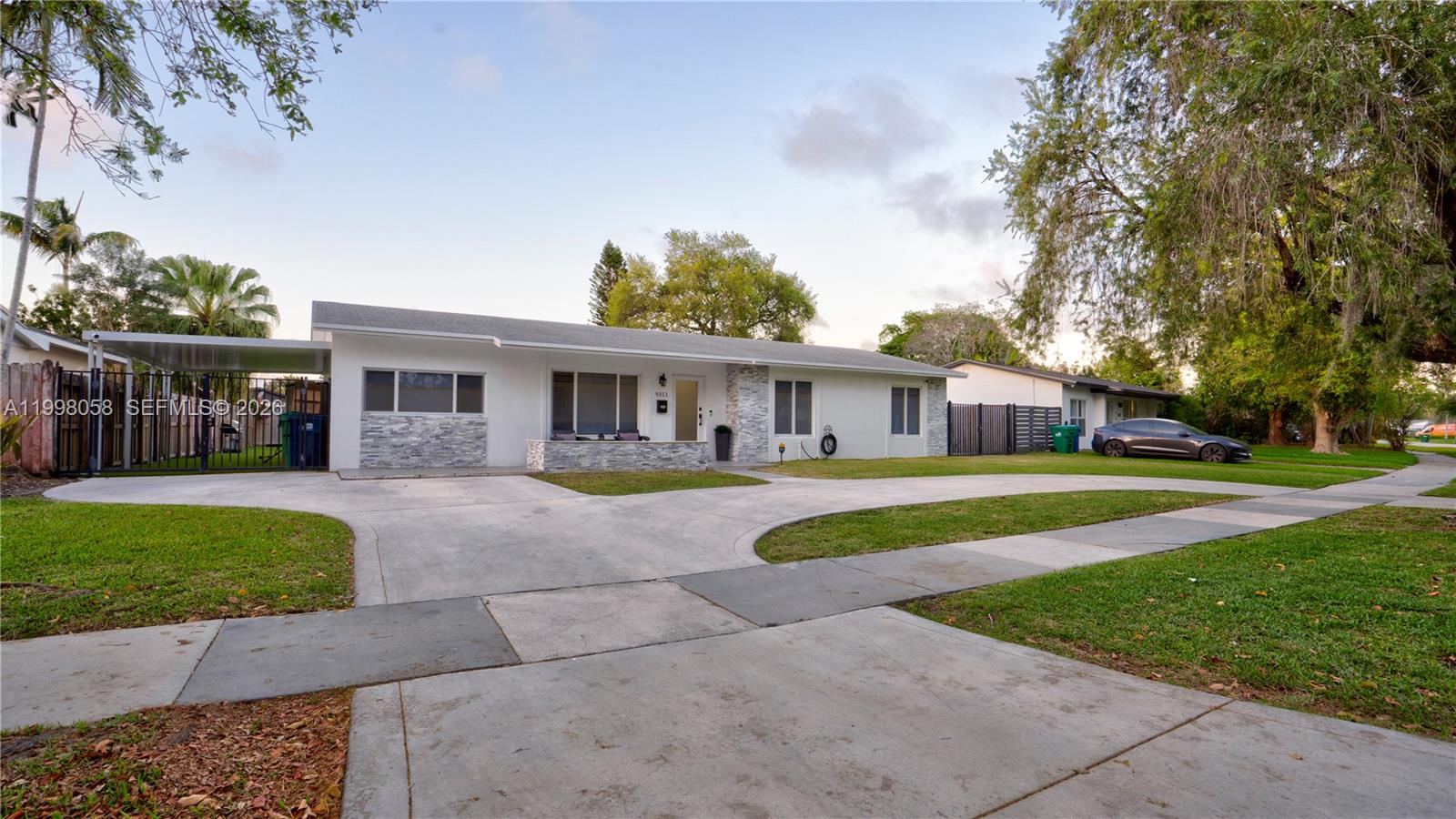 A single-story house with a white exterior, stone accents, and a wide concrete driveway — 9311 Sterling Dr, Cutler Bay FL 33157, CUTLER BAY, FL