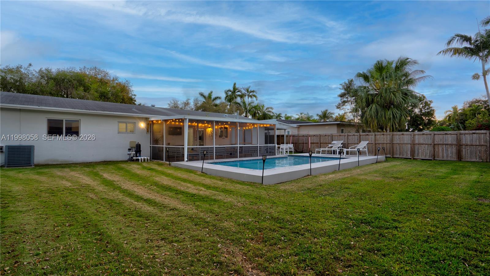 A backyard features a swimming pool, a screened-in patio, and a wooden fence — 9311 Sterling Dr, Cutler Bay FL 33157, CUTLER BAY, FL