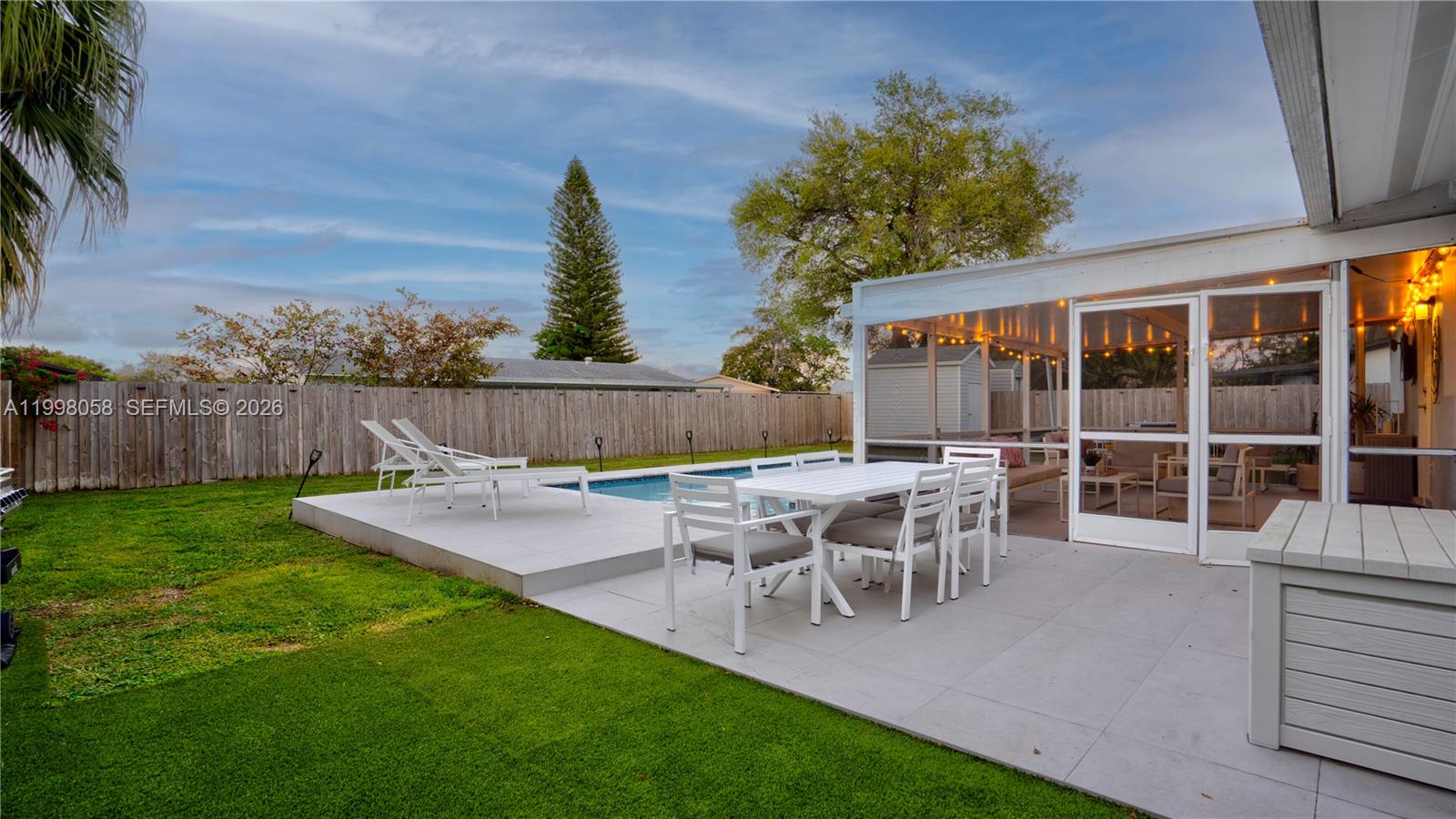 A backyard features a swimming pool, a patio with dining furniture, and a screened enclosure — 9311 Sterling Dr, Cutler Bay FL 33157, CUTLER BAY, FL
