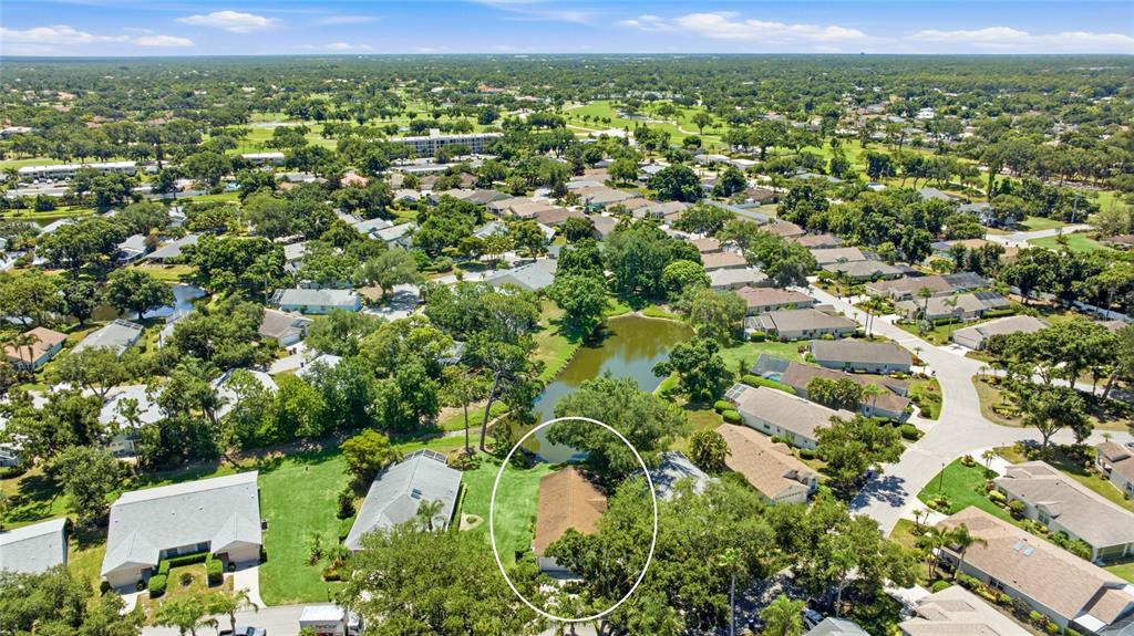 An aerial view shows a residential neighborhood with a house circled near a small pond — 7317 ELEANOR CIRCLE UNIT 176, SARASOTA, FL
