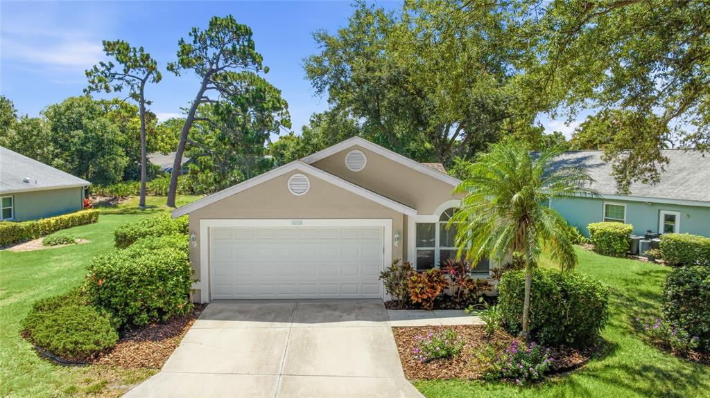 A tan single-story house with a two-car garage, palm tree, and landscaped front yard — 7317 ELEANOR CIRCLE UNIT 176, SARASOTA, FL