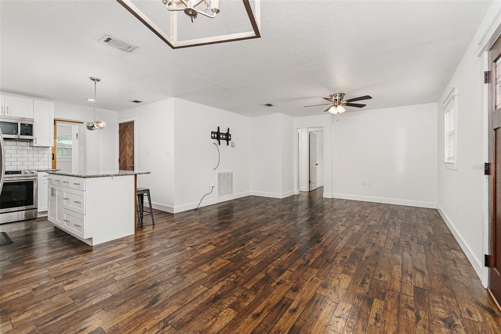 An open-concept living area features white walls, dark wood flooring, and a kitchen island — 2220 MINI RANCH ROAD, LAKELAND, FL