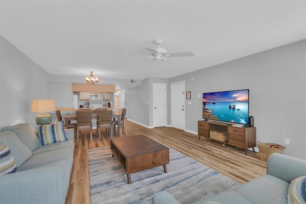 A living room with light gray walls, wood-look flooring, a ceiling fan, and a dining area — 5004 LAGUNA BAY CIRCLE UNIT 49, KISSIMMEE, FL