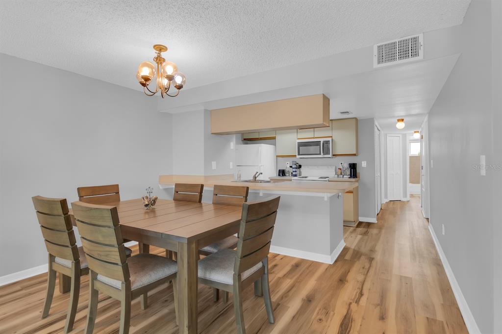 A dining area with a wooden table and chairs sits adjacent to an open kitchen — 5004 LAGUNA BAY CIRCLE UNIT 49, KISSIMMEE, FL
