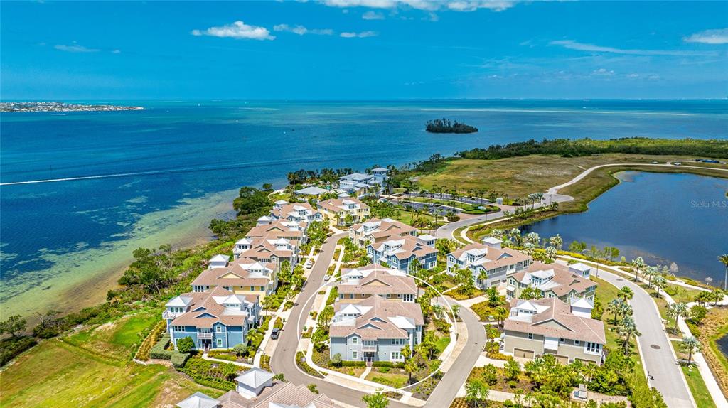 An aerial view shows a coastal residential community with multiple houses near a large bay — 283 SAINT LUCIA DRIVE UNIT 101, BRADENTON, FL