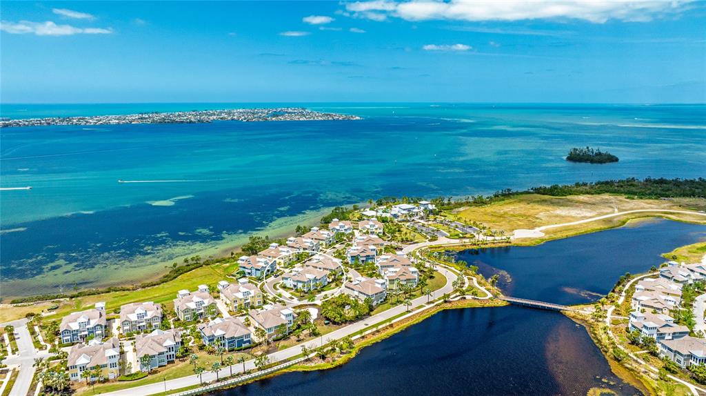 An aerial view shows a coastal residential community situated between a large bay and lake — 283 SAINT LUCIA DRIVE UNIT 101, BRADENTON, FL
