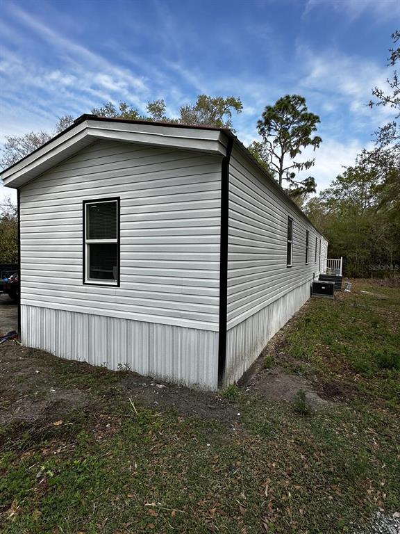 The exterior of a white mobile home with horizontal siding and a metal skirt — 343 CREEKWOOD RUN, LAKELAND, FL