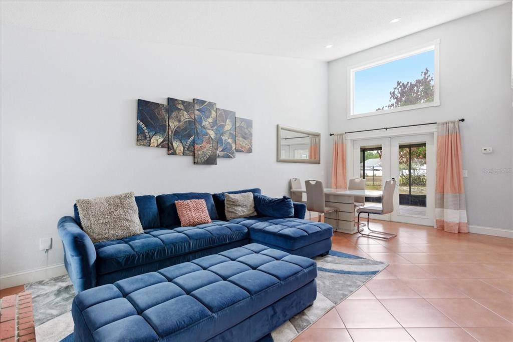 A living room features a blue sectional sofa, a matching ottoman, and a dining area — 7811 WORTHAM COURT, ORLANDO, FL