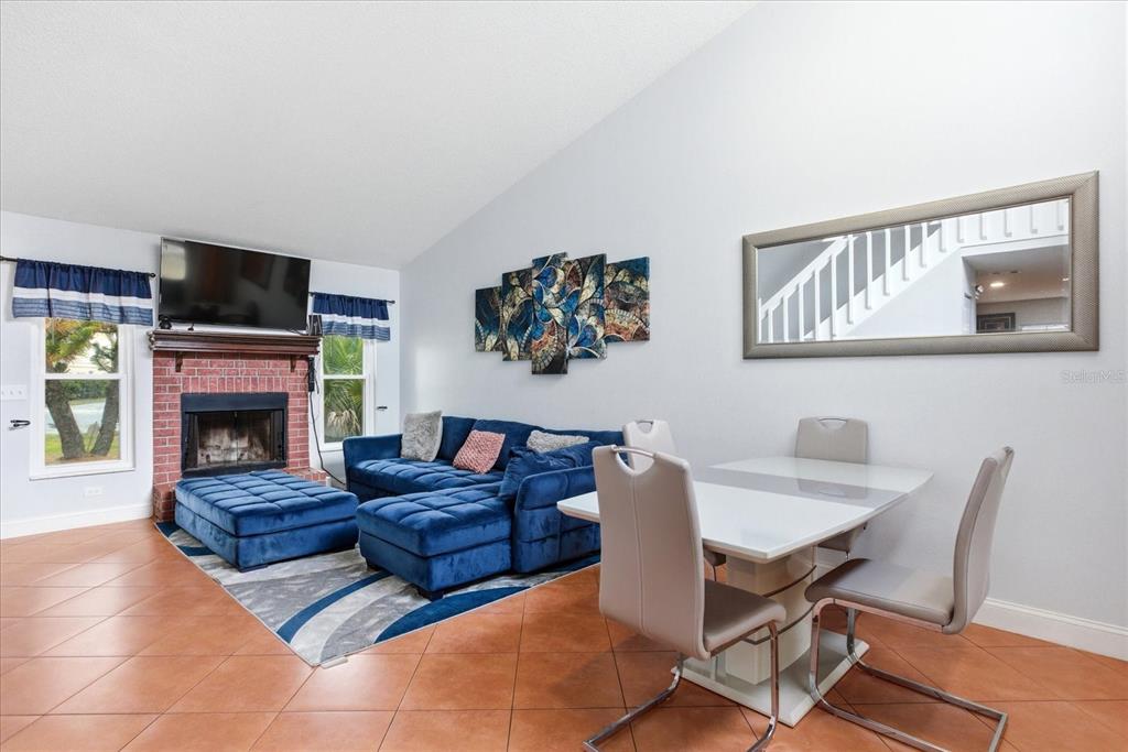 A living and dining area features a brick fireplace, blue sectional sofa, and white table — 7811 WORTHAM COURT, ORLANDO, FL