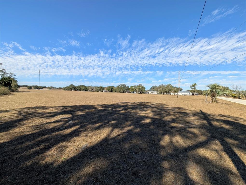 A wide, dry, grassy field under a blue sky with scattered clouds — 122-125 MILLER STREET, POMONA PARK, FL