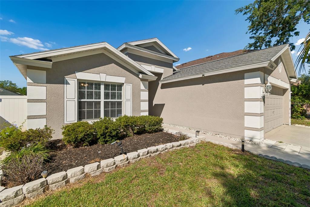 A single-story house with a beige stucco exterior, white trim, and a front-facing garage — 13226 EVENING SUNSET LANE, RIVERVIEW, FL