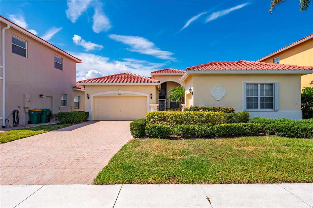 A single-story house with a tan exterior, red tile roof, and a paved driveway — 24311 RIVERFRONT DRIVE, PUNTA GORDA, FL