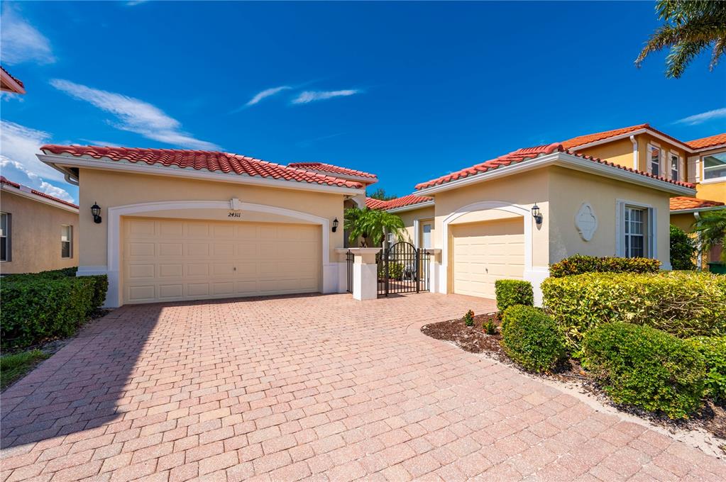 A beige house with a red tile roof and a brick paver driveway — 24311 RIVERFRONT DRIVE, PUNTA GORDA, FL