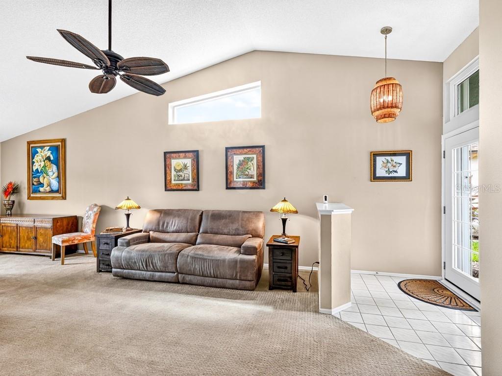 A living room features a vaulted ceiling, a brown leather sofa, and a tiled entryway — 4322 EDENROSE WAY UNIT 86, SARASOTA, FL