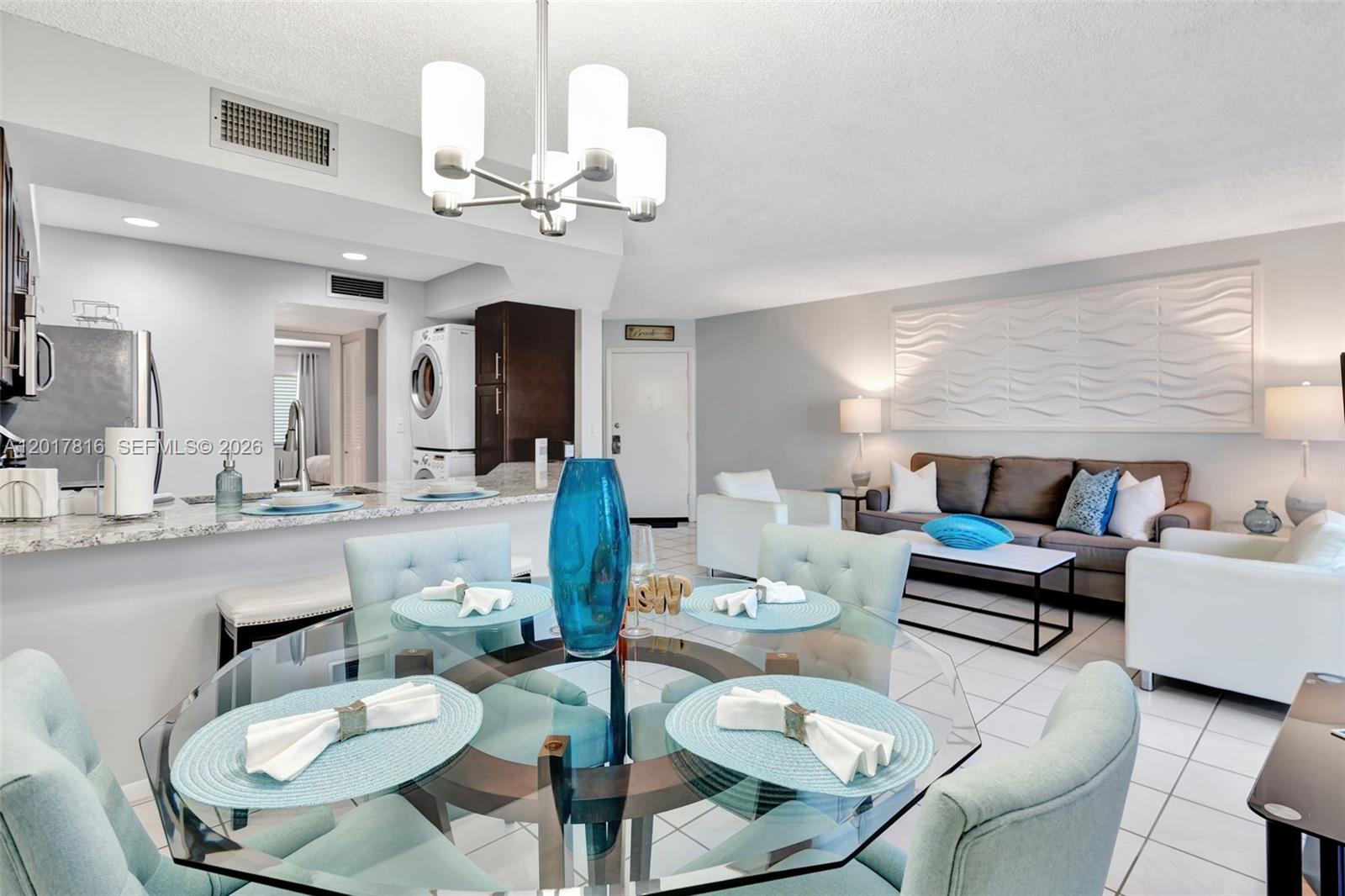 A dining area with a glass table and light blue chairs opens into a living room — 1605 S Us Highway 1, Jupiter FL 33477, JUPITER, FL