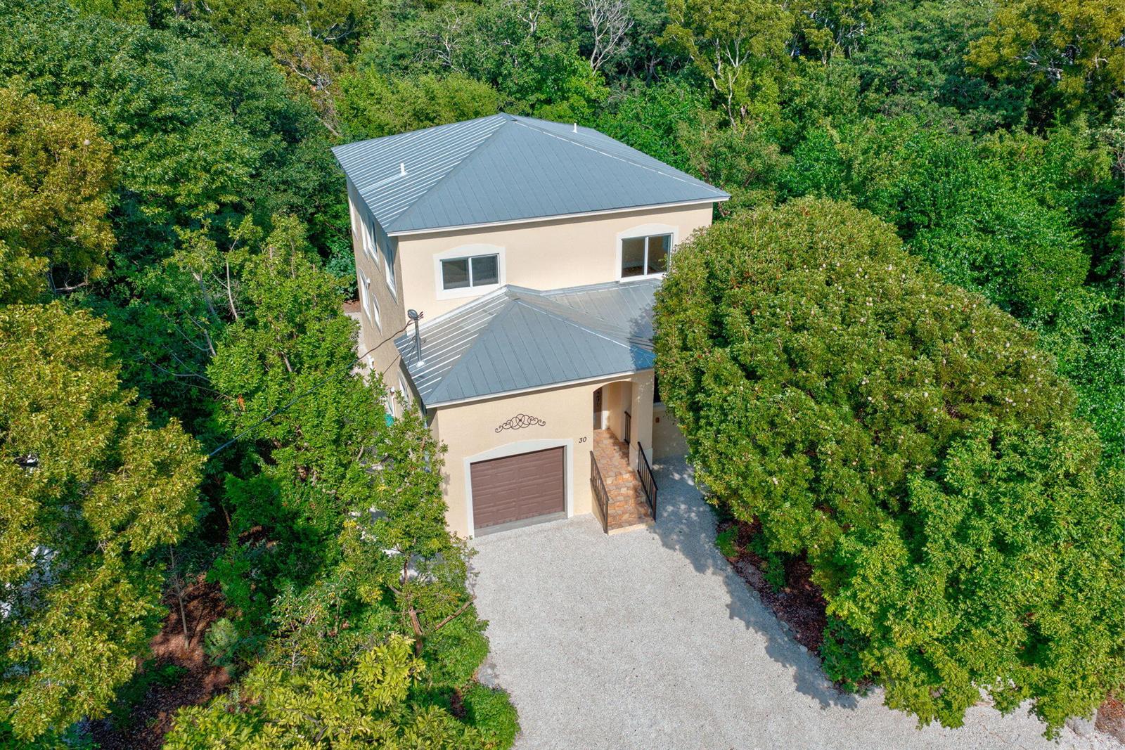 The exterior of a house features a garage, tiled front steps, and a glass door — 30 Seagate Boulevard, Key Largo FL 33037, KEY LARGO, FL
