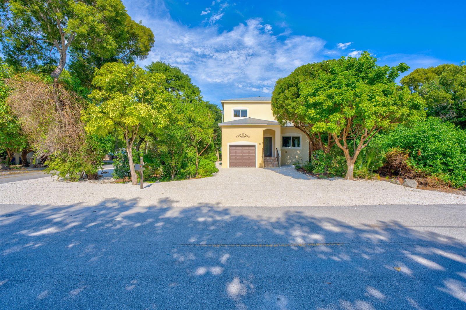 A gravel driveway leads to a house partially obscured by trees and dense foliage — 30 Seagate Boulevard, Key Largo FL 33037, KEY LARGO, FL