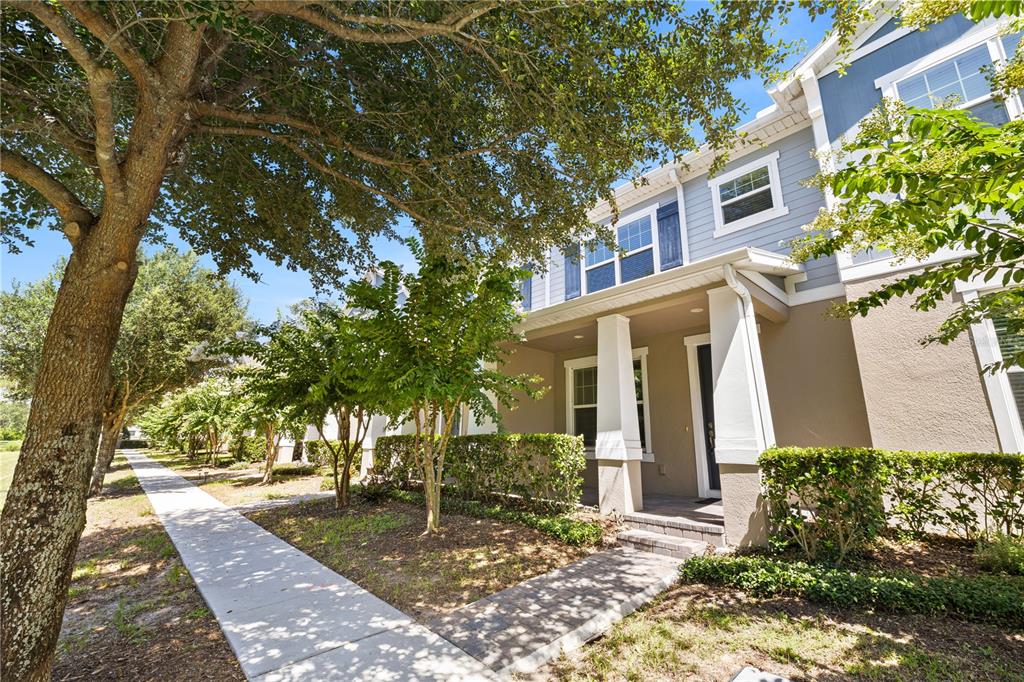 A two-story townhouse exterior features a covered entryway, light blue siding, and a paved walkway — 10509 SPRING ARBOR LANE, WINTER GARDEN, FL