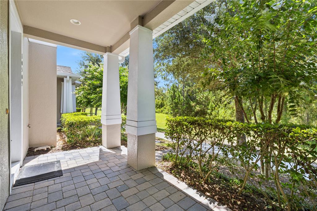 A covered front porch with stone pavers and white columns overlooks a landscaped yard — 10509 SPRING ARBOR LANE, WINTER GARDEN, FL