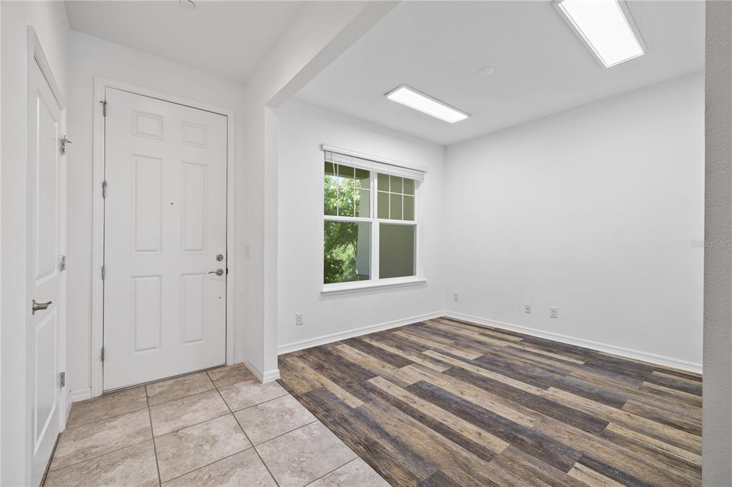 An entryway with tiled flooring transitions into a room featuring wood-look flooring and windows — 10509 SPRING ARBOR LANE, WINTER GARDEN, FL