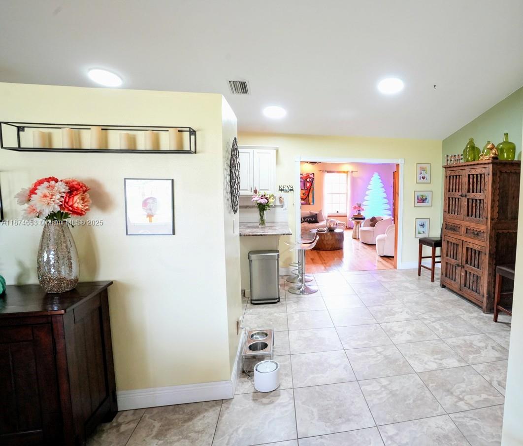 A tiled entryway leads into a kitchen and living area with light yellow walls — 2304 SE 8TH TER, Cape Coral FL 33990, CAPE CORAL, FL