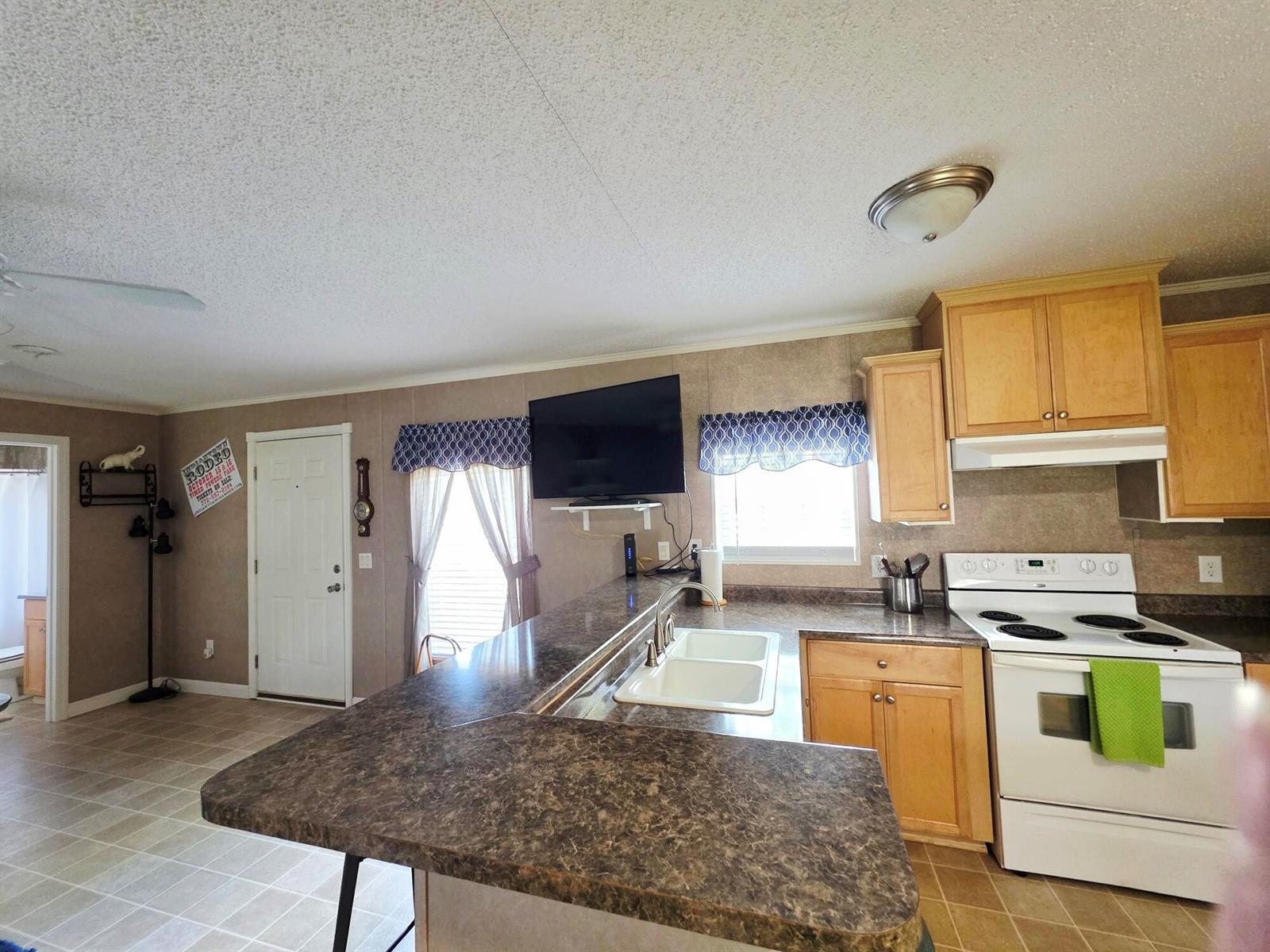 A kitchen with light wood cabinets, dark laminate countertops, and a white stove — 1501 Lake Drive W, Okeechobee FL 34974, OKEECHOBEE, FL