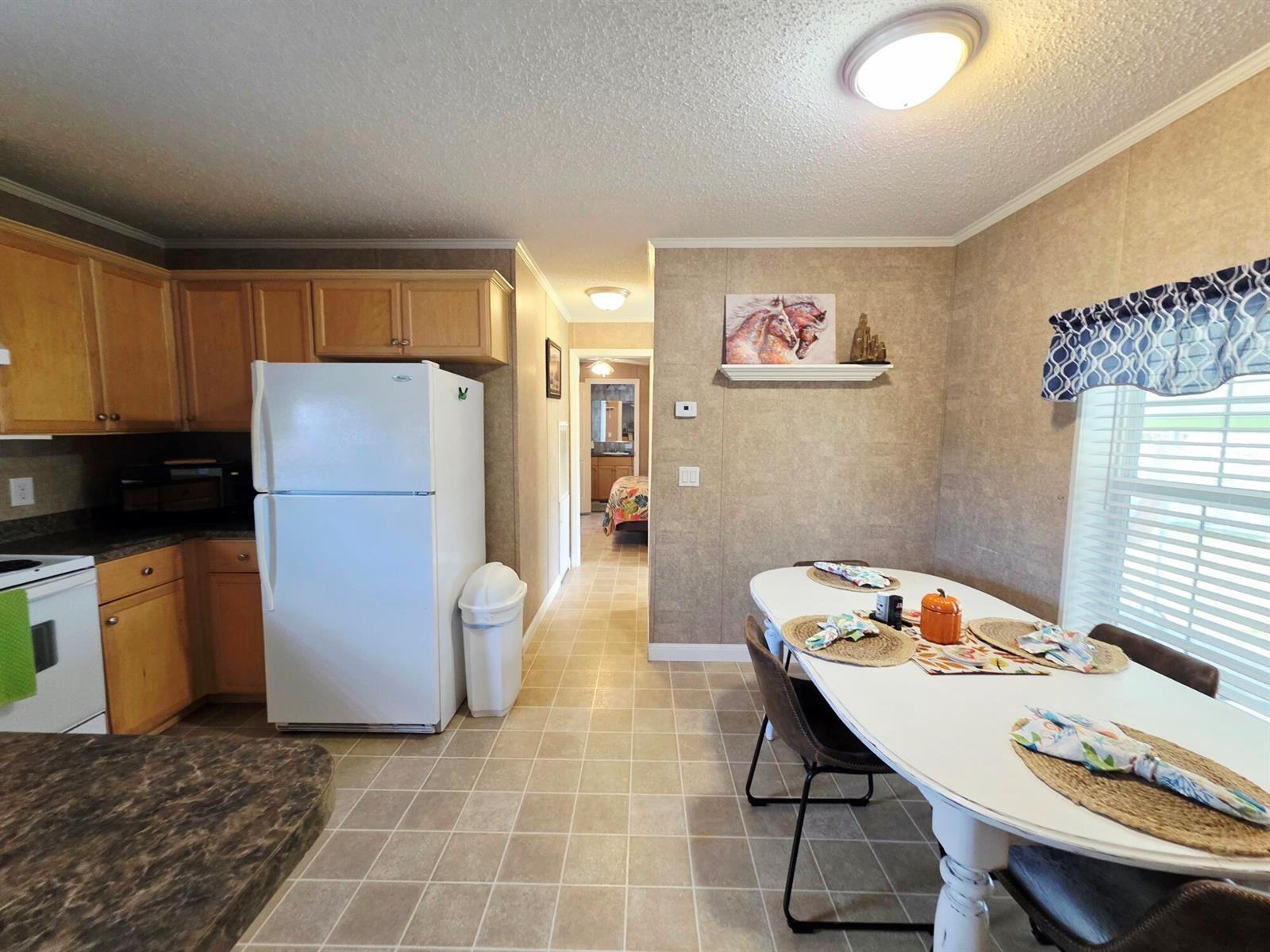 A kitchen and dining area featuring light wood cabinets, a white refrigerator, and tile flooring — 1501 Lake Drive W, Okeechobee FL 34974, OKEECHOBEE, FL