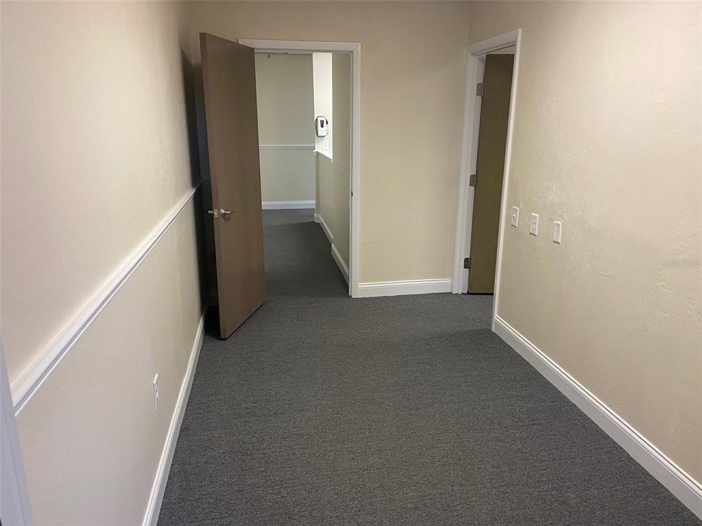A carpeted hallway leads to two open doorways with brown doors and beige walls — 3501 SW 2ND AVENUE UNIT 2400, GAINESVILLE, FL