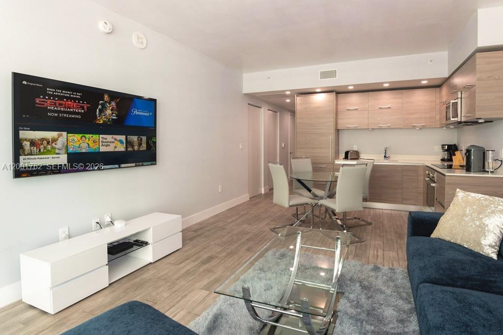 A modern open-concept living area features a kitchen, dining table, and wall-mounted television — 1300 S Miami ave. # 3908, Miami FL 33130, MIAMI, FL