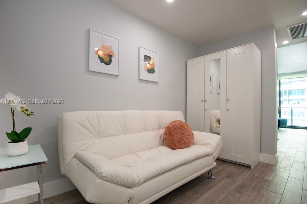 A white sofa sits in a room with light gray walls, a wardrobe, and artwork — 1300 S Miami ave. # 3908, Miami FL 33130, MIAMI, FL