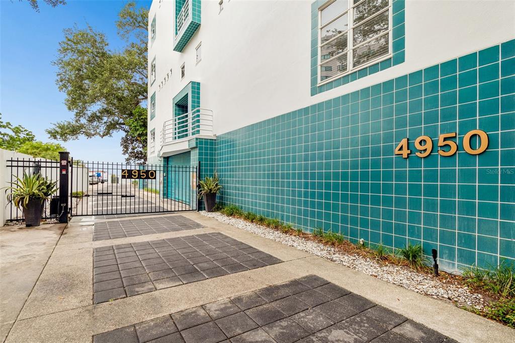 The exterior of a white building features teal square tiles and a gated driveway — 4950 BAYSHORE BOULEVARD UNIT 30, TAMPA, FL