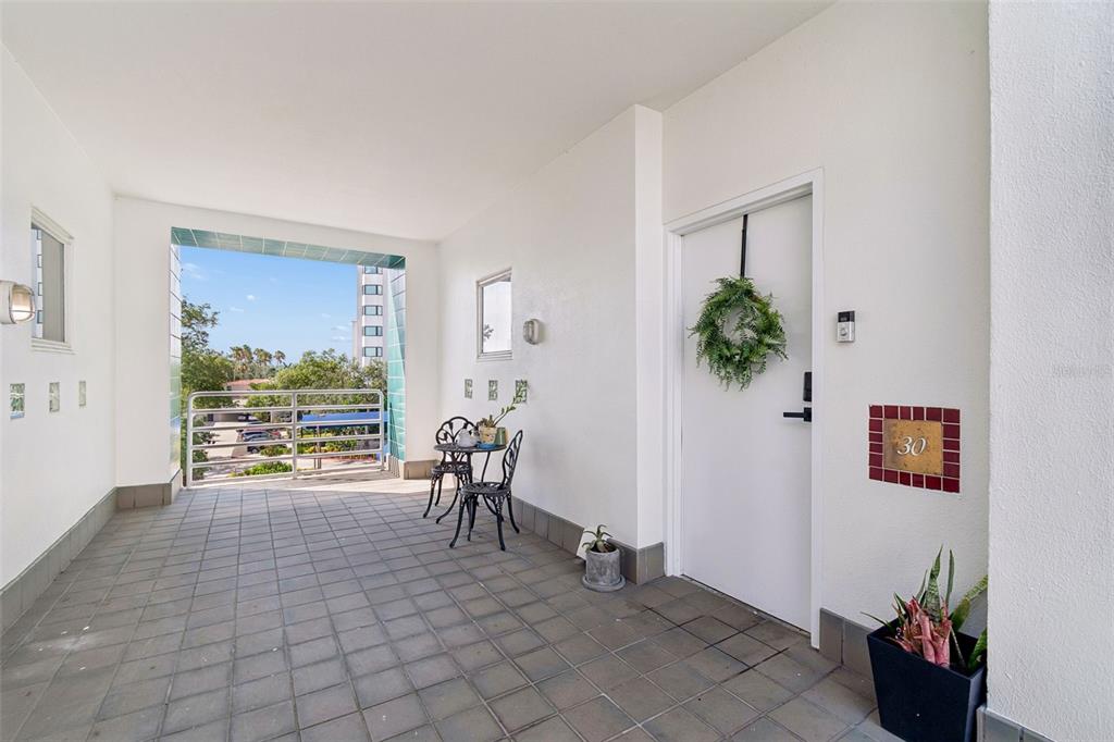 A covered outdoor patio features tiled flooring, a small bistro set, and a white door — 4950 BAYSHORE BOULEVARD UNIT 30, TAMPA, FL