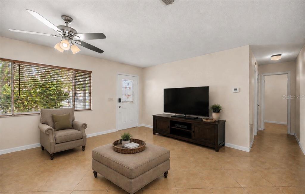 A living room features tile flooring, a ceiling fan, a television console, and an armchair — 10358 SE 178 PLACE, SUMMERFIELD, FL