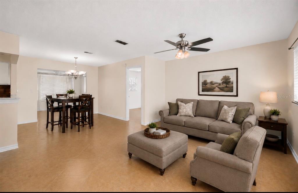 A living room and dining area feature beige tile floors, neutral walls, and furniture — 10358 SE 178 PLACE, SUMMERFIELD, FL
