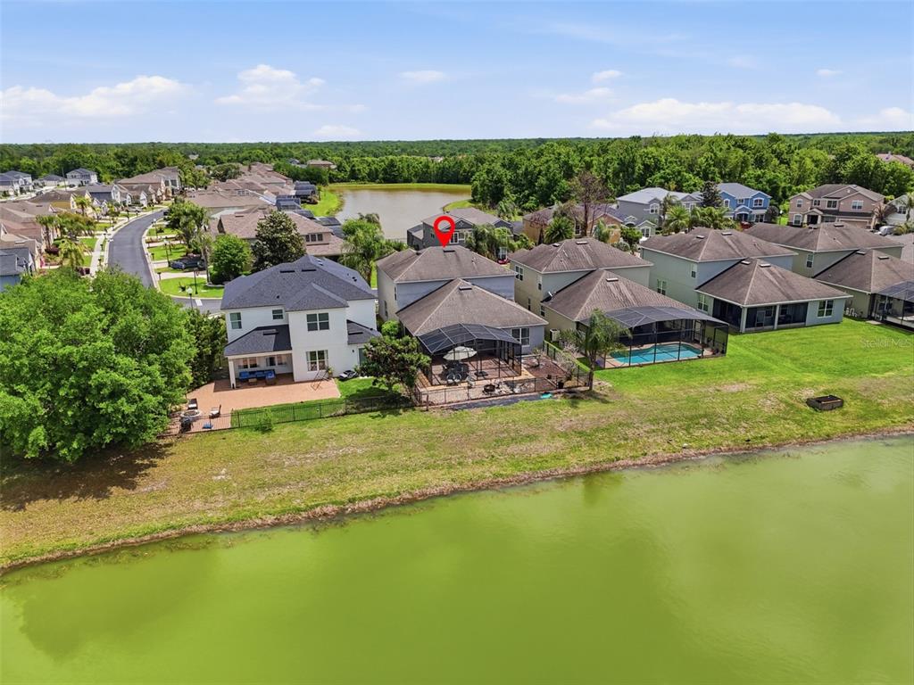 An aerial view shows several suburban houses with screened-in pools situated along a lake — 1409 BROOKHAVEN COURT, DAVENPORT, FL
