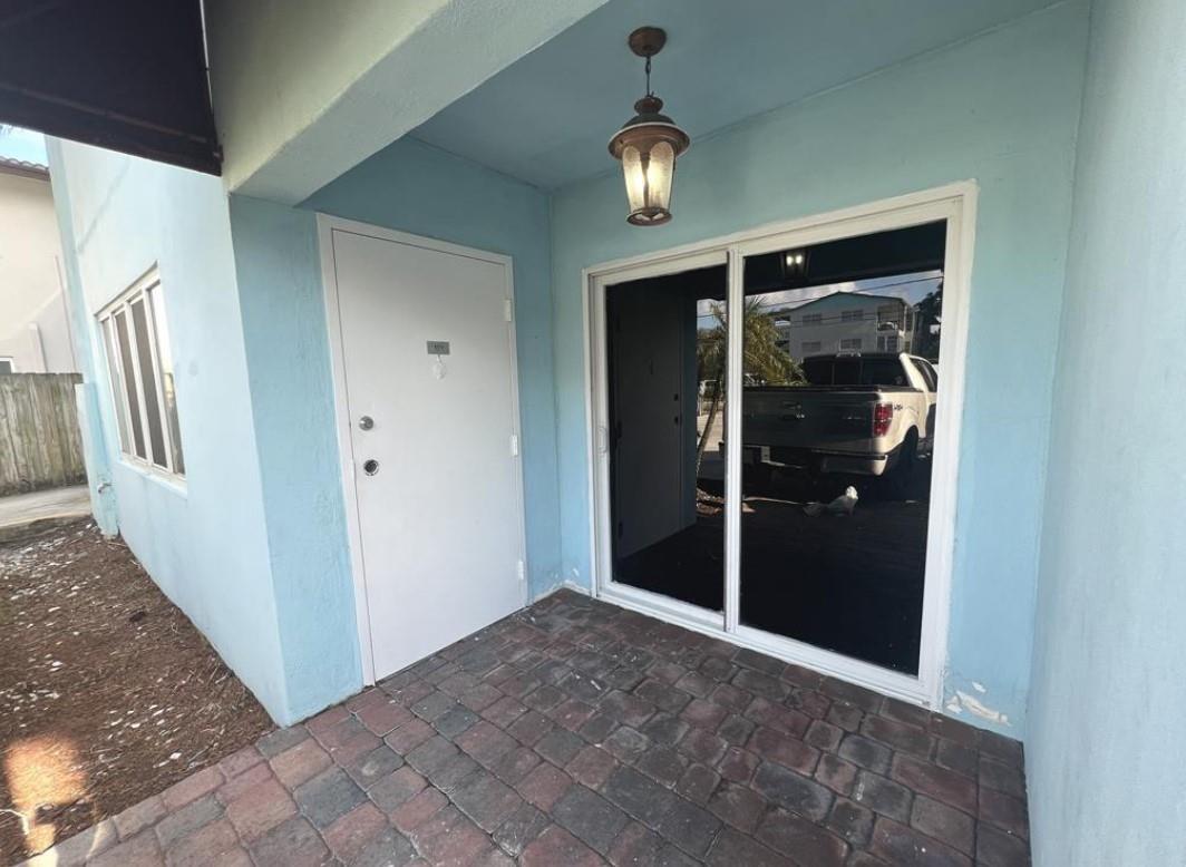 A light blue exterior wall features a white entry door and a sliding glass door — 1060 Crystal Lake Drive # 101, Deerfield Beach FL 33064, DEERFIELD BEACH, FL