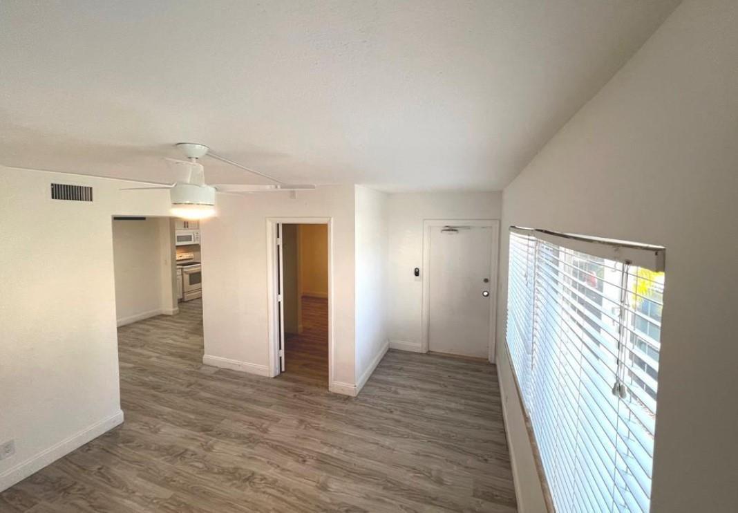 An interior view of a living room with light wood-look flooring and a ceiling fan — 1060 Crystal Lake Drive # 101, Deerfield Beach FL 33064, DEERFIELD BEACH, FL