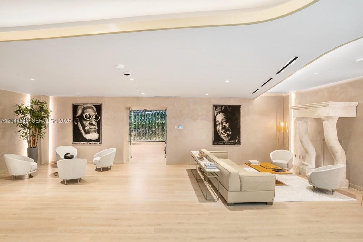 A spacious, minimalist living area features light wood floors, neutral walls, and two large portraits — 1000 Brickell Plz # 3410, Miami FL 33131, MIAMI, FL
