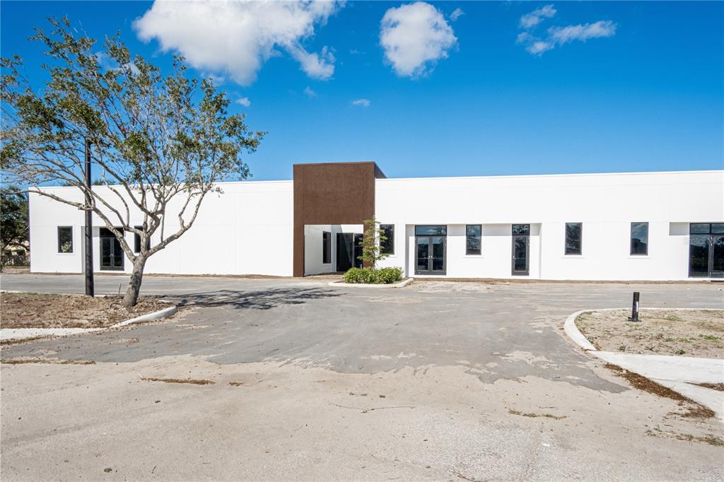 A modern, single-story commercial building with white walls and a central brown accent section — 11125 CORRIDOR PLACE, BRADENTON, FL