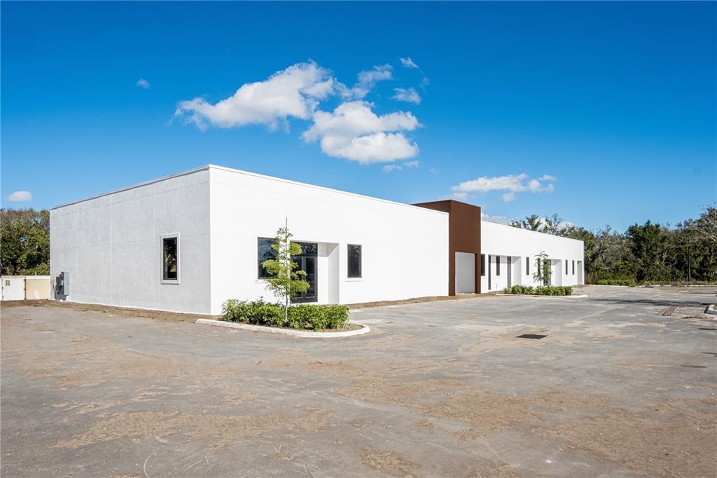 A modern, single-story white commercial building with a brown accent wall and a paved lot — 11125 CORRIDOR PLACE, BRADENTON, FL