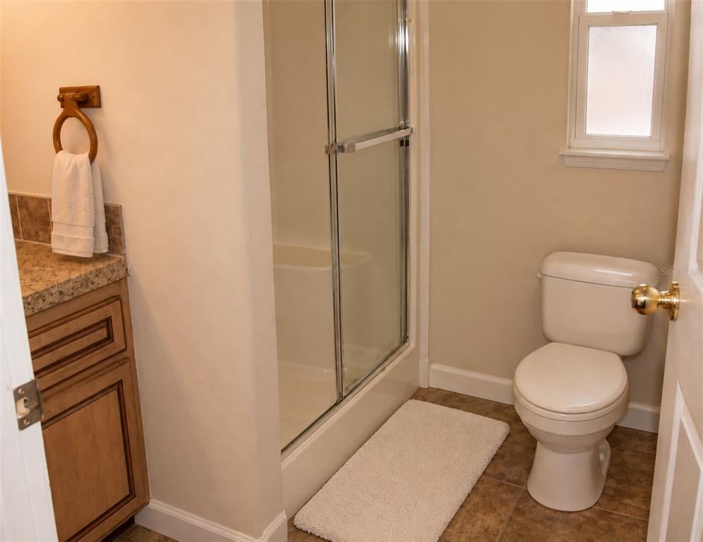 A bathroom features a vanity with a stone countertop, a glass-enclosed shower, and a toilet — 791 35TH AVENUE S, ST PETERSBURG, FL