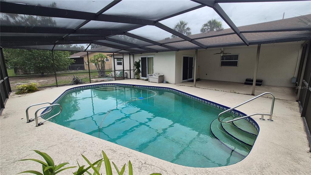 A screened-in swimming pool with a concrete deck sits behind a single-story residential home — 4625 CANTERBURY DRIVE, LAND O LAKES, FL