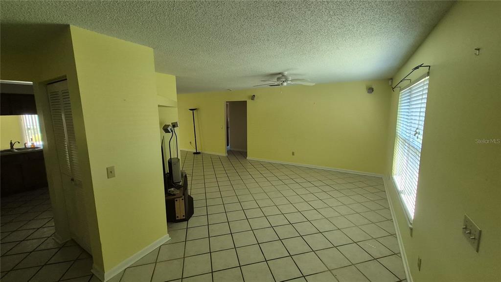 An empty living room features yellow walls, white tile flooring, and a ceiling fan — 4625 CANTERBURY DRIVE, LAND O LAKES, FL