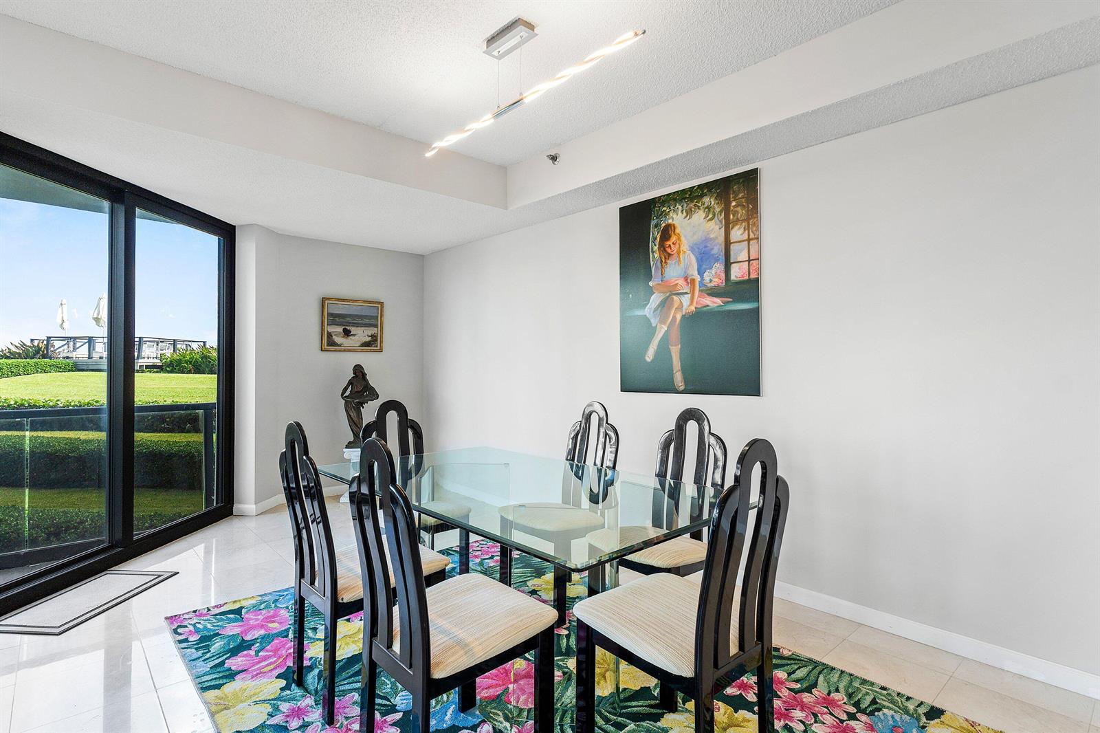 A dining room features a glass table, black chairs, a floral rug, and large windows — 3120 S Ocean Boulevard # 101, Palm Beach FL 33480, PALM BEACH, FL
