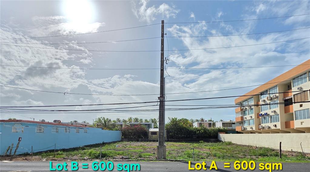 A vacant, grassy lot is situated between a blue wall and a multi-story apartment building — 16 OCEAN DRIVE AVENUE LOTS A & B, LUQUILLO, PR