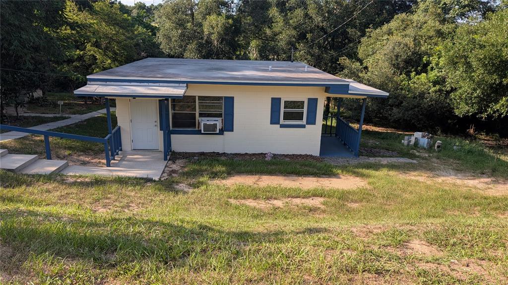 A small, single-story house with cream-colored block walls, blue trim, and a flat roof — 738 E MINNEOLA AVENUE, CLERMONT, FL