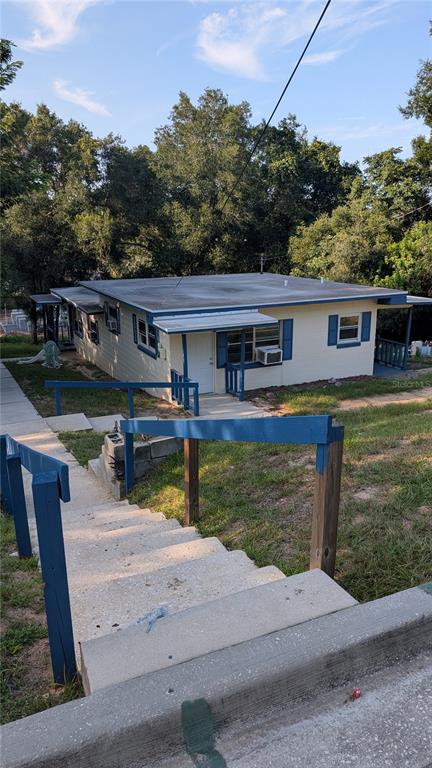 A light-colored house with blue trim sits at the bottom of a concrete staircase — 738 E MINNEOLA AVENUE, CLERMONT, FL