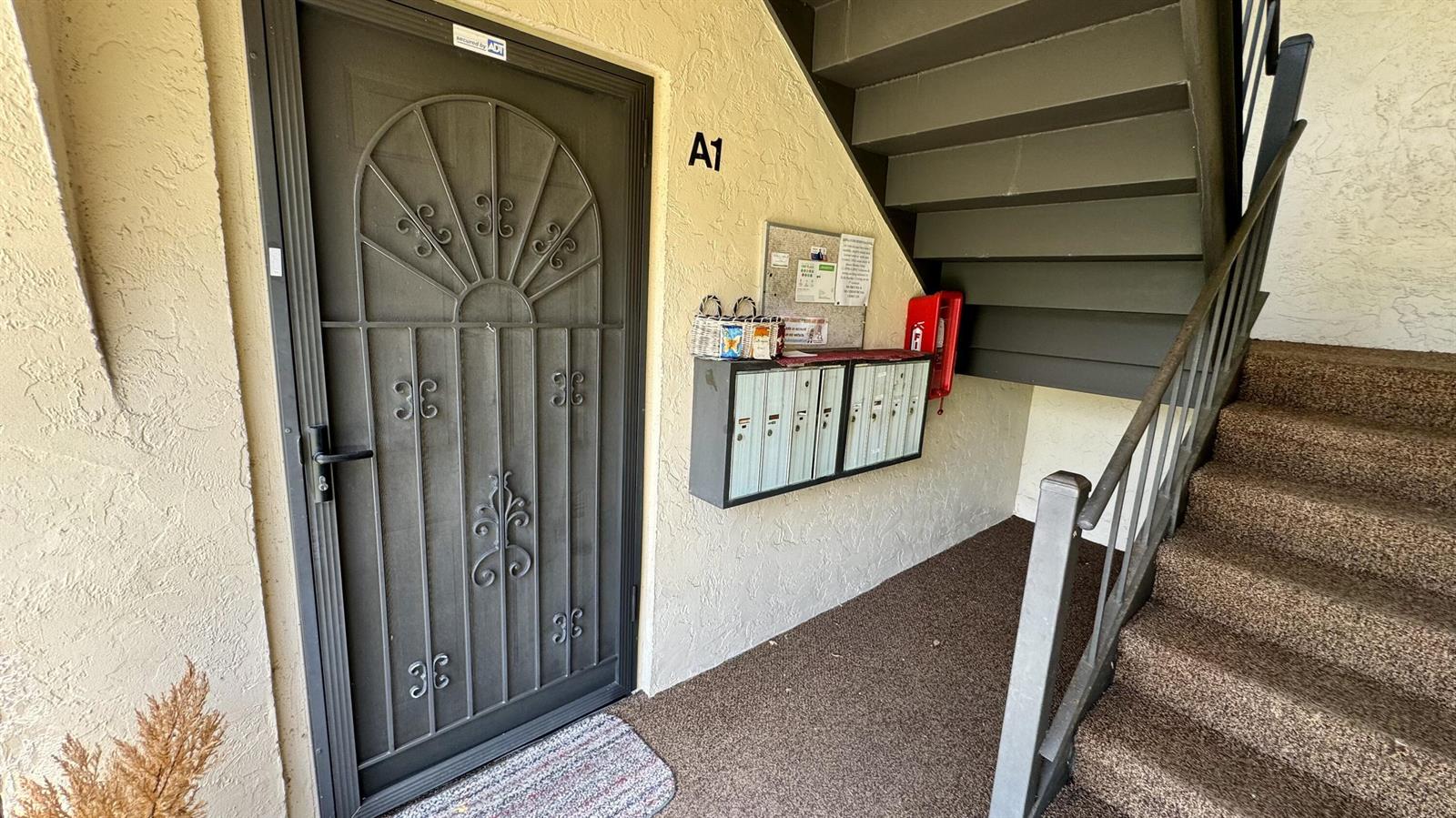 An apartment entrance features a security screen door, a row of mailboxes, and stairs — 104 Lake Pine Circle # 1, FL 33463, FL
