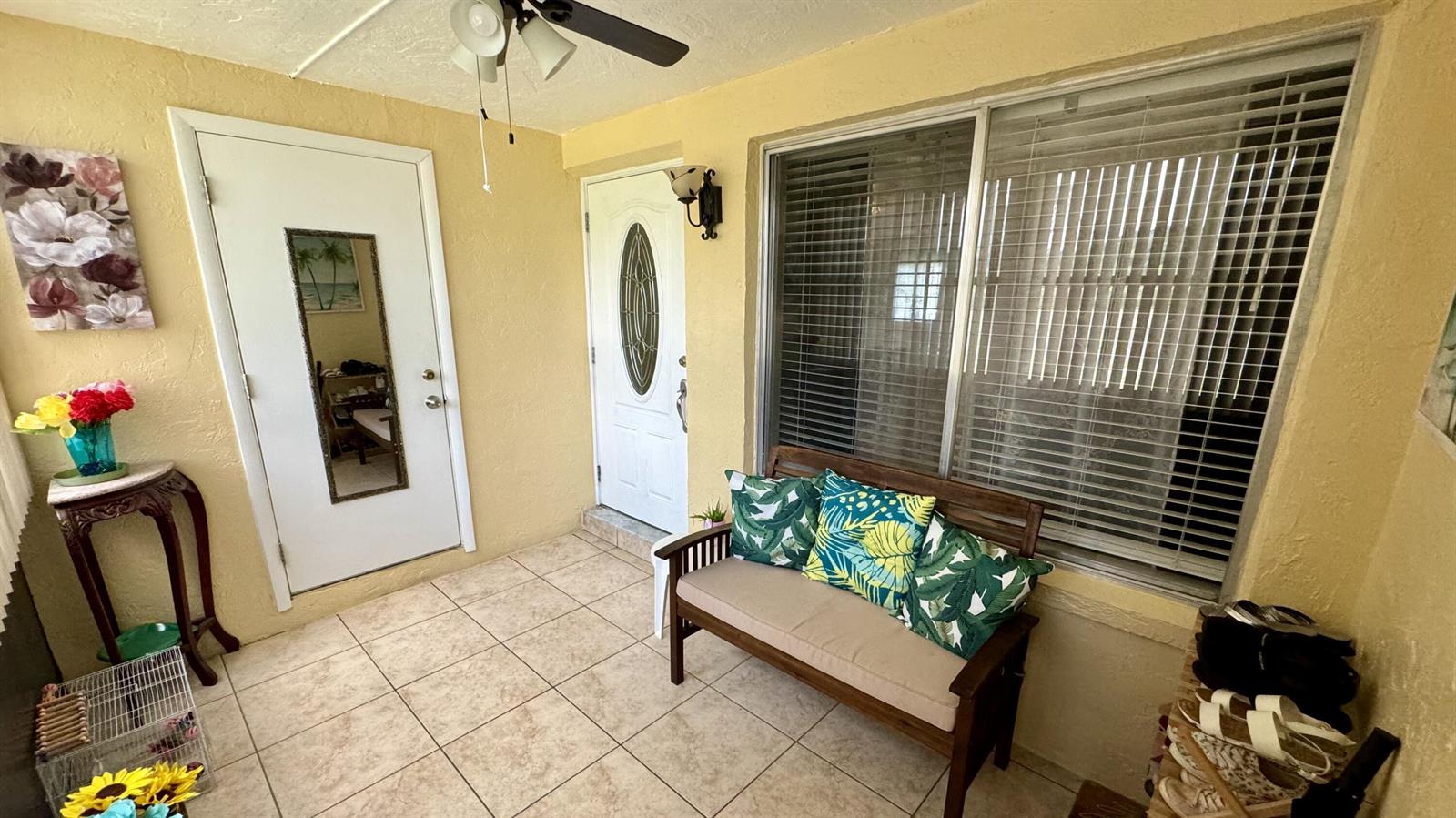 A sunroom with tile flooring, a wooden bench, two white doors, and a ceiling fan — 104 Lake Pine Circle # 1, FL 33463, FL