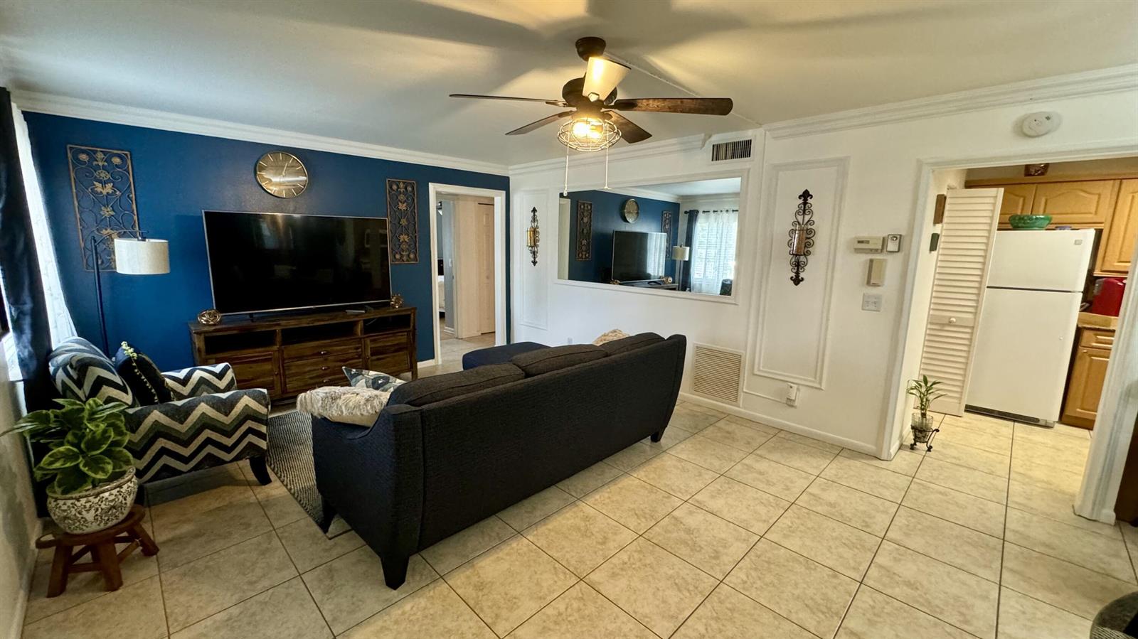 A living room features a blue accent wall, a dark sofa, and tile flooring — 104 Lake Pine Circle # 1, FL 33463, FL